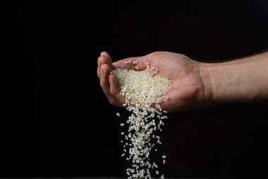 Pirinç siyah arka planda inliyor. Pirinç, koyu bir zemine dökülüyor.