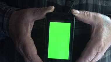 Erkek elleri yeşil ekranlı cep telefonunu yukarıda tutuyor. 