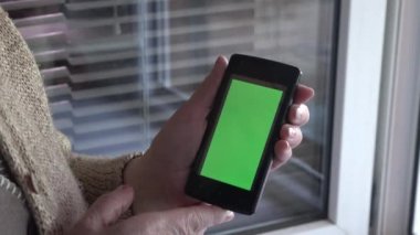Kadın elleri yeşil ekranlı cep telefonunu tutuyor 