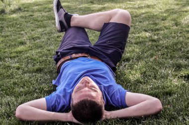 Genç adam yalan aşağı çim zemin üzerine