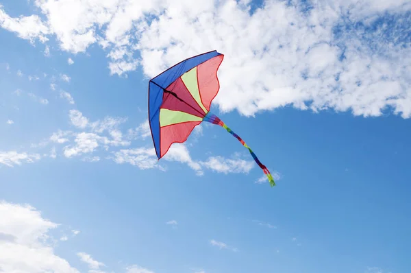 Cerf-volant arc-en-ciel lumineux coloré planant dans le ciel bleu avec des nuages blancs — Photo