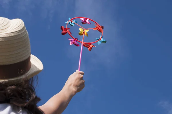 Jeune femme tenant coloré arc-en-ciel lumineux jouet roue à aiguilles contre le ciel bleu — Photo