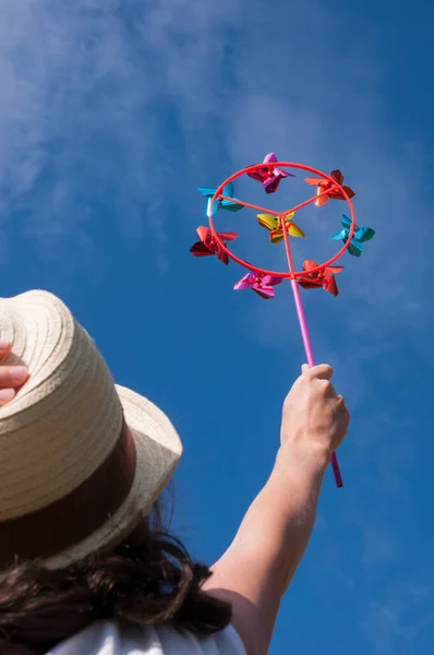 Jeune femme tenant coloré arc-en-ciel lumineux jouet roue à aiguilles contre le ciel bleu — Photo