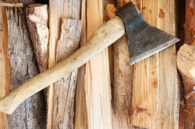 Ahşap saplı eski bir balta yakacak odun yığınının üzerinde duruyor.