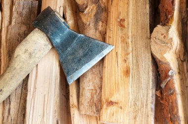 Ahşap saplı eski bir balta yakacak odun yığınının üzerinde duruyor.