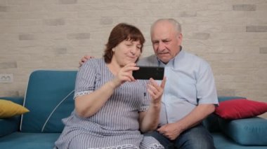 Kafkasyalı emekli, yeni akıllı telefon uygulaması için yaşlı karısı tarafından yardım ediliyor..