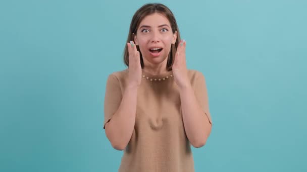Detailní záběr ženy s omráčený a šokovaný pohled na tyrkysovém pozadí. — Stock video