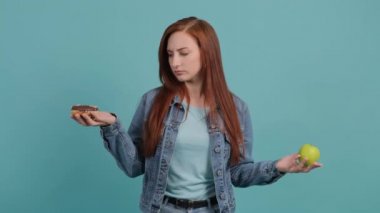 Elma ve donut arasında seçim yapan genç bir kadın..