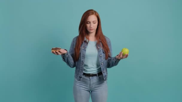 Giovane donna che sceglie tra mela e ciambelle, la ragazza sceglie mela. — Video Stock