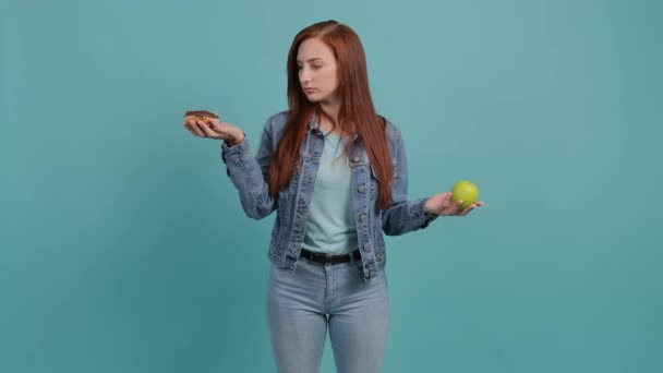 Giovane donna che sceglie tra mela e ciambelle, la ragazza sceglie ciambelle. — Video Stock