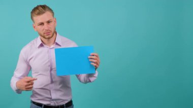 Sakallı mutlu genç bir adam elinde tuttuğu mavi bir çarşafı işaret eder..