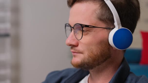 Joven escuchando música en los auriculares y bebiendo una taza de café. — Vídeo de stock