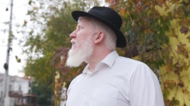 Beyaz gömlekli ve şapkalı albinizmli yaşlı bir adama yaklaş..