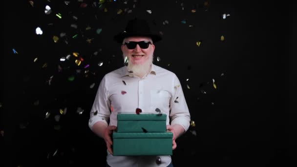 Buntes Konfetti fällt vor einem Albino-Mann mit Geschenkbox in der Hand nieder. — Stockvideo