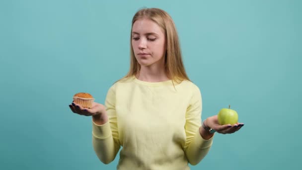 Junge Frau wählt zwischen Apfel und Cupcake, das Mädchen wählt Cupcake. — Stockvideo