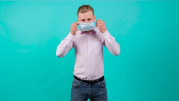 Snygg man sätter på sig en mask i ansiktet från luftföroreningar och coronavirus. — Stockvideo