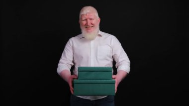 Kalbinden bir hediye kutusu veren yakışıklı albino adam kameraya bakıyor..