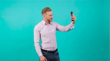 Yakışıklı adam görüntülü konuşuyor ve el sallayarak selam veriyor..