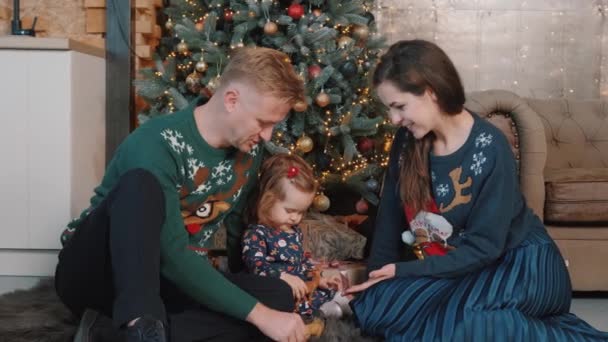 Jovem casal brincando com sua filhinha perto da árvore de Natal em casa. — Vídeo de Stock