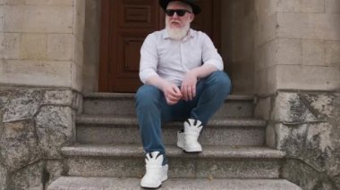 Albinizmden muzdarip bir adam dışarıda oturup sigara içiyor...