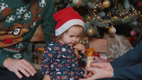Close up de uma menina que está brincando com seus pais perto da árvore de Natal. — Vídeo de Stock