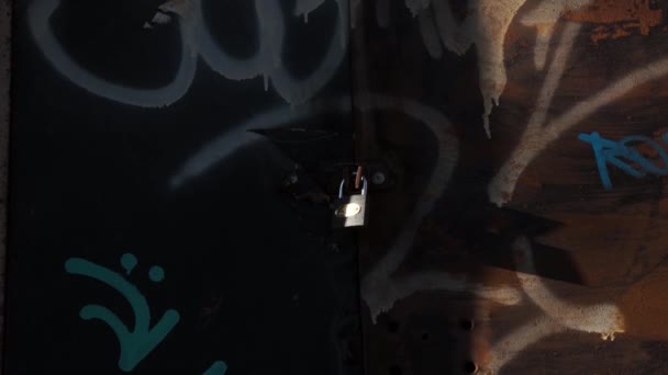 Un candado colocado en unas viejas puertas con graffiti. — Vídeos de Stock