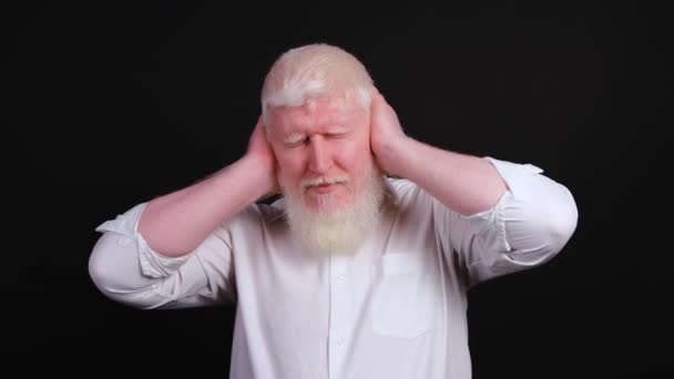 Kulaklarını elleriyle kapatan, başını sallayan albino bir adamın yakınına.. — Stok video