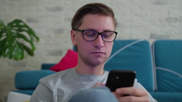 Junger Mann surft mit Handy im Internet und bleibt zu Hause isoliert. — Stockvideo