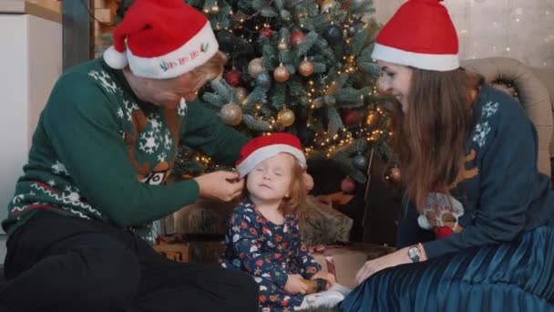 Schönes Paar spielt mit kleiner Tochter in der Nähe des Weihnachtsbaums. — Stockvideo