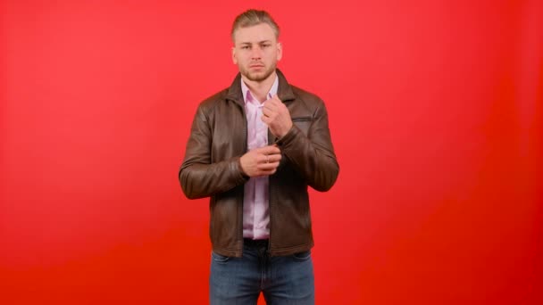 Casual άνθρωπος στέκεται και τακτοποίηση σακάκι σε κόκκινο φόντο στούντιο. — Αρχείο Βίντεο