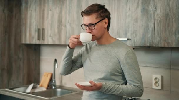 O homem está bebendo café forte quente de uma xícara branca enquanto faz uma pausa do trabalho. — Vídeo de Stock