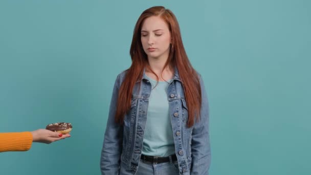 Junge Frau, die sich einem Donuts verweigert und zeigt, dass sie einen Apfel hat. — Stockvideo