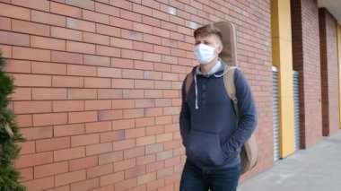 Genç adam tıbbi maskeyi taktı ve arkada gitarla dışarı çıktı..