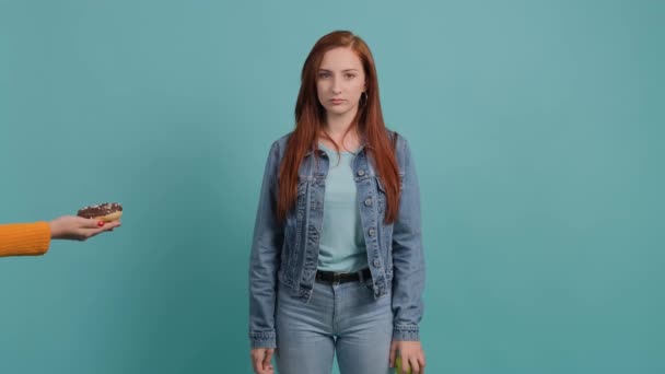 Nahaufnahme einer jungen Frau, die sich einem Donuts verweigert und zeigt, dass sie einen Apfel hat. — Stockvideo