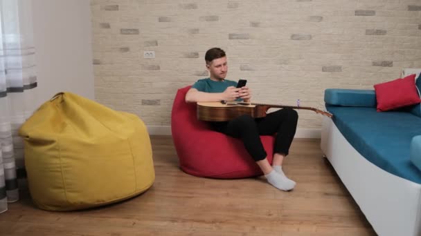 Jongeman met een gitaar in zijn armen schrijft een boodschap aan zijn vriendin — Stockvideo