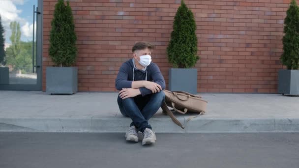 의료용 마스크를 쓴 한 젊은이가 주위를 둘러보고 일어나서. — 비디오