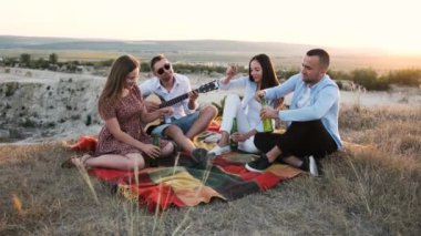 Dört neşeli insan piknikte şişeyi açıp birayla tezahürat yapıyor..