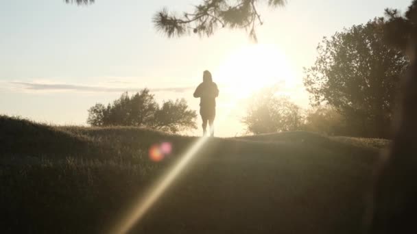 Νεαρός τρέχει στο πάρκο το ηλιοβασίλεμα για να βελτιώσει την υγεία του. — Αρχείο Βίντεο