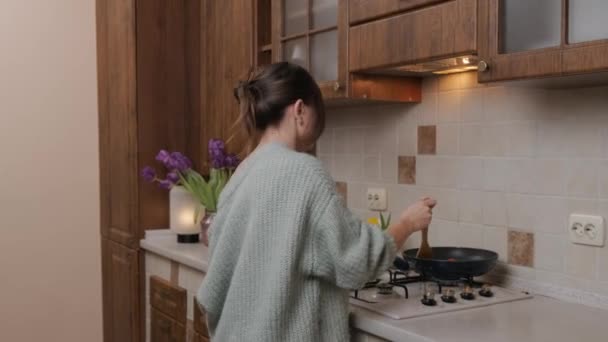 Junger Mann schenkt seiner Frau, die in der Küche das Essen zubereitet, Blumen. — Stockvideo
