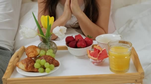 Reggeli az ágyban, a nő kivesz egy epret, hogy felszolgálja a férjét.. — Stock videók