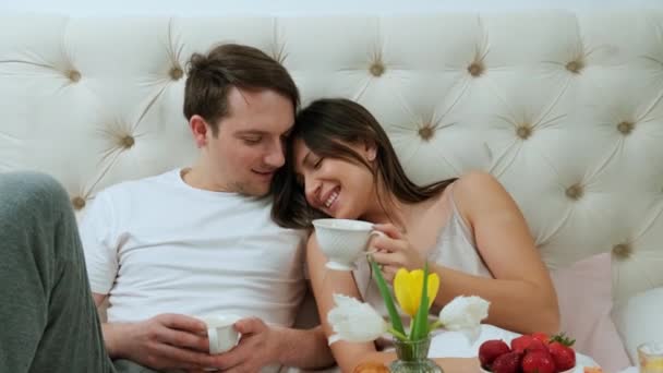 Schönes Paar hat Spaß, frühstückt im Bett und trinkt eine Tasse Kaffee. — Stockvideo