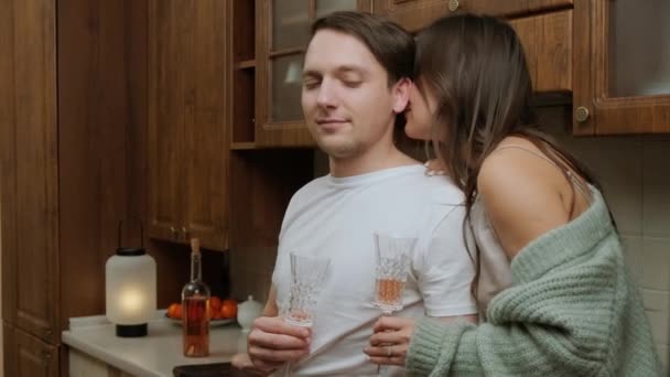 Ρομαντικό νεαρό ζευγάρι που απολαμβάνει ένα ποτήρι κρασί και χαλαρώνει στην κουζίνα. — Αρχείο Βίντεο