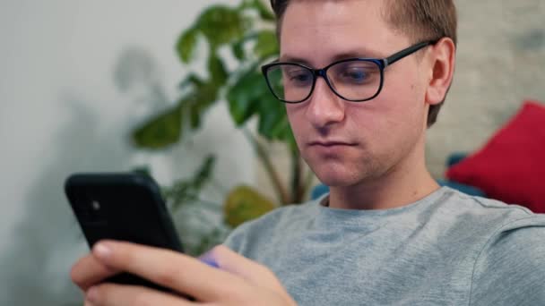 Junger Mann surft mit Handy im Internet und bleibt zu Hause isoliert. — Stockvideo