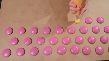 Şef pembe ve turuncu kurabiyelerden yapar, dolguyu fırın kağıdına döker..
