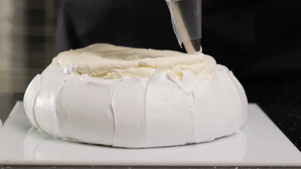 Chef de pastelaria enche brownies creme com saco de pastelaria. Processo de fazer Bolo Anna Pavlova. — Vídeo de Stock