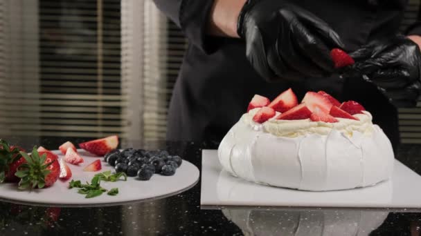 Pastry chef decorates Anna Pavlovas cake with fresh fruiets and mint leaves. — Stock Video