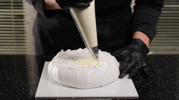 Bucătarul de patiserie umple negrese cremă cu sac de patiserie. Procesul de a face tort Anna Pavlova . — Videoclip de stoc