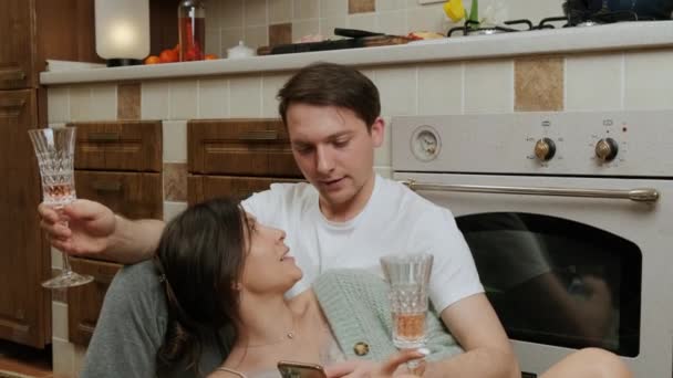 Casal romântico que gosta de um copo de vinho e relaxar na cozinha no chão. — Vídeo de Stock