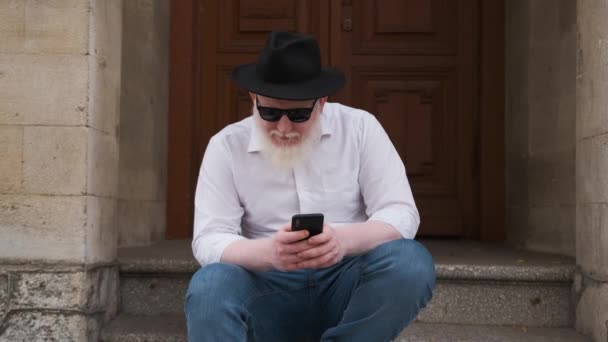 Homem que sofre de albinismo senta-se fora e navegar na internet. — Vídeo de Stock