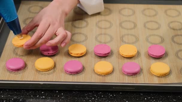 Chef de pastelaria está enchendo macarons com creme usando um saco de pastelaria. — Vídeo de Stock